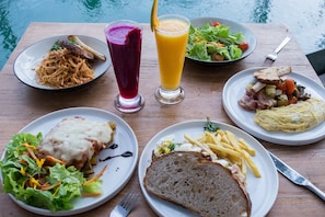 Una mesa de madera con varios platos de comida, como pasta, pan y una ensalada.