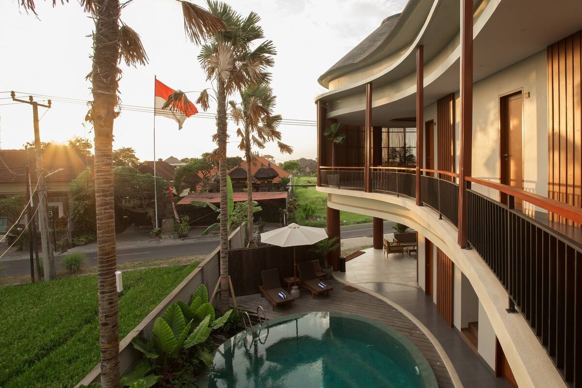 A hotel with a pool, outdoor seating, and a view of the surrounding area.