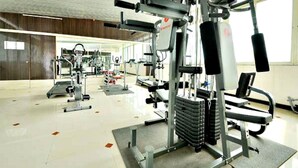 Un gimnasio con diversos equipos de ejercicio, que incluyen máquinas de pesas y pesas libres.