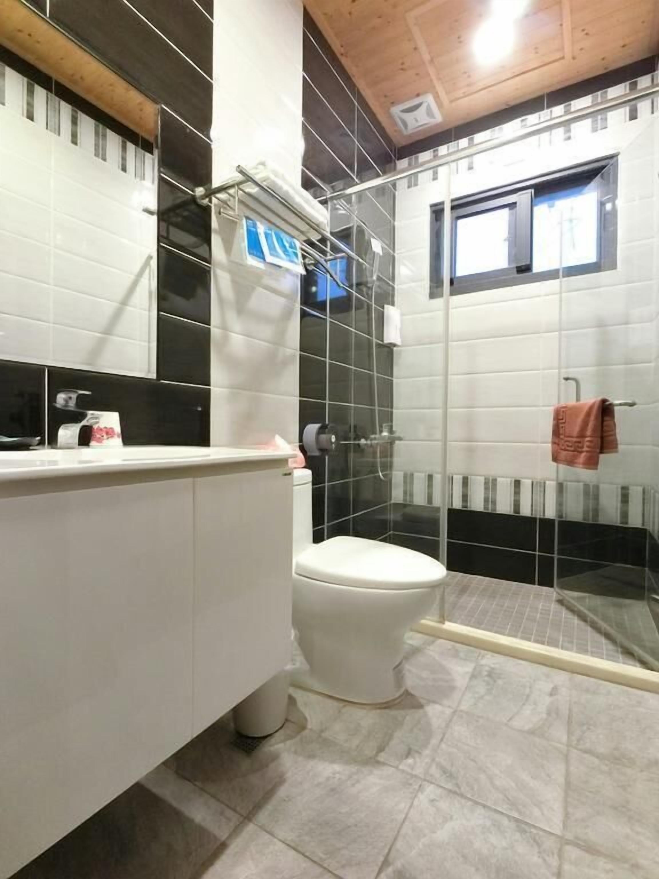 A modern bathroom with a white toilet, a glass shower enclosure, and a white vanity with a mirror.