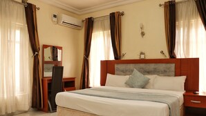 A hotel room with a bed, a desk, a chair, and a mirror. - Bayse One Premium (Ibadan)