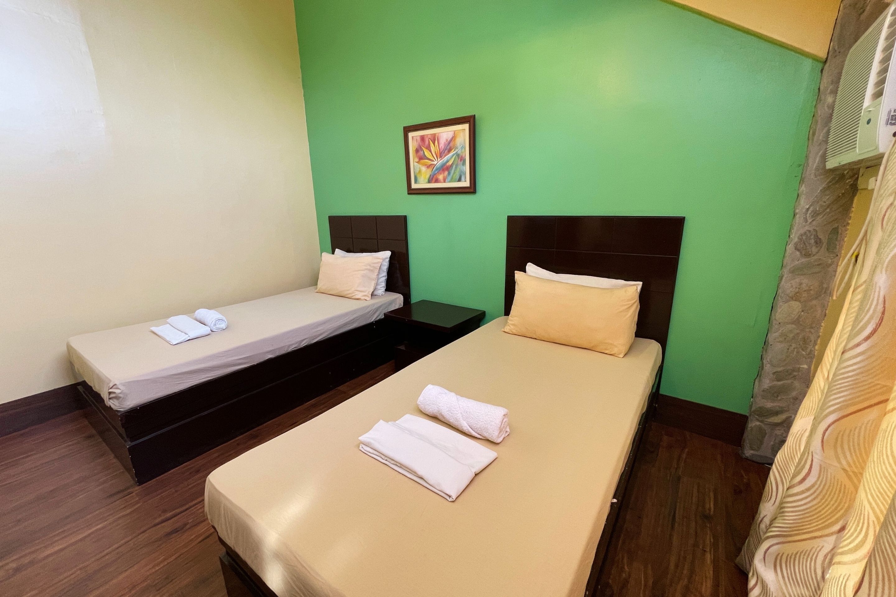 A room with two beds, each with a pillow and a rolled towel.