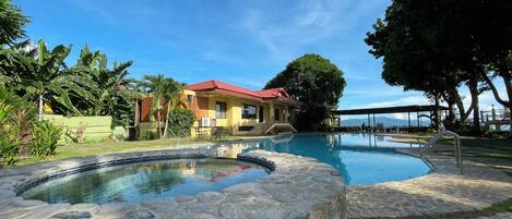 A swimming pool with stone edges, a red-roofed building, and lush greenery.