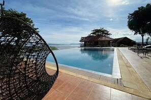 A pool area with a wicker chair, a building with a red roof, and a view of the sea. - Punta de Fabian powered by Cocotel (Baras)