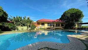 A swimming pool with stone tiles, surrounded by a building with a red roof and a yellow facade, and lush greenery. - Punta de Fabian powered by Cocotel (Baras)