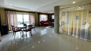 A spacious living area with a dining table and chairs, a red sofa, and a bed with a canopy. - Punta de Fabian powered by Cocotel (Baras)