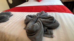 A neatly made bed with a red and white striped bedspread, a red pillow, and two gray towels. - Downtown Siem Reap Villa (Siem Reap)