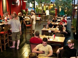 A restaurant with multiple tables and chairs, some occupied by diners.