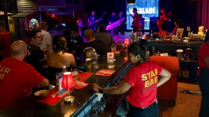 A bar area with a stage for live music, bar stools, and a counter with a bartender. - Downtown Siem Reap Villa (Siem Reap)