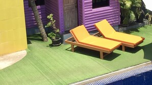 A purple house with a red roof, a small door, and two windows. There are two yellow lounge chairs and a small table outside. - Downtown Siem Reap Villa (Siem Reap)