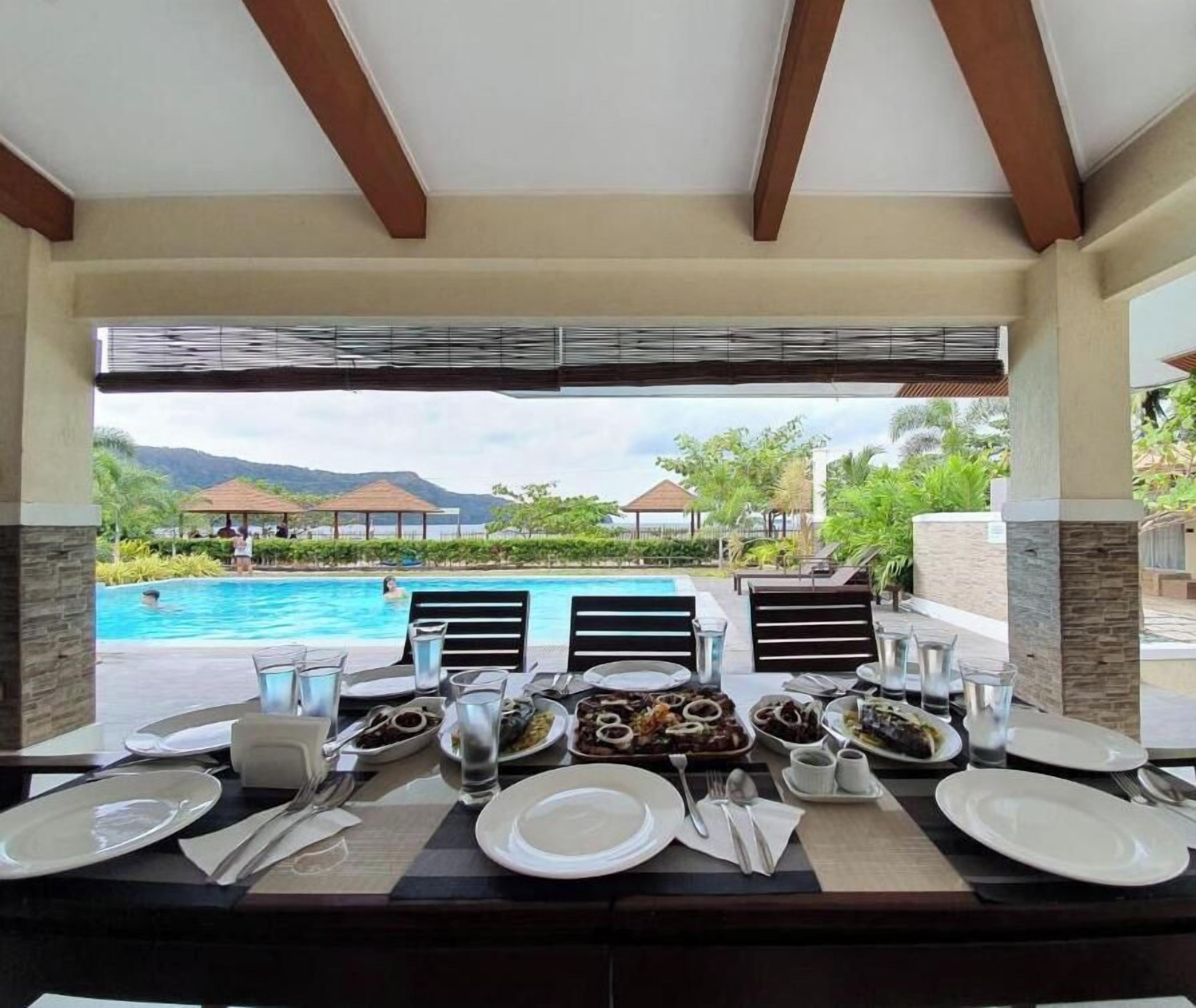 A dining table set for two with a view of a pool and mountains.