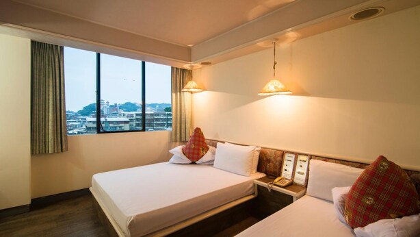 A hotel room with a large bed, bedside tables, and a view of the city through the window. - Dahua Hotel (Keelung)