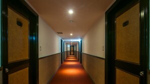 A hotel hallway with carpeted floors, wooden doors, and a ceiling light. - Dahua Hotel (Keelung)