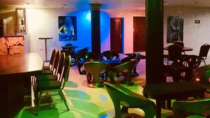Une pièce faiblement éclairée, avec un bar, plusieurs chaises et une table.