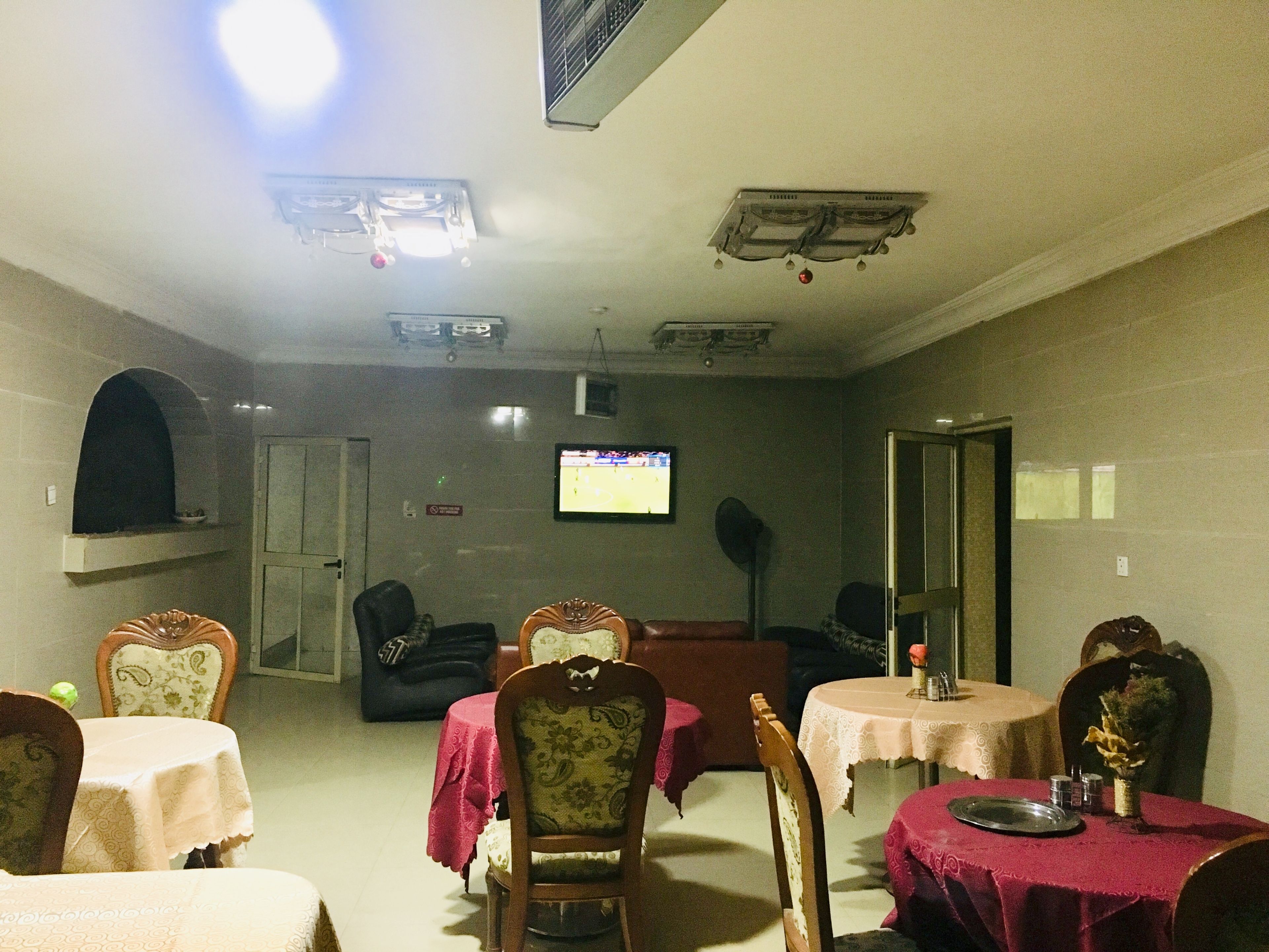 A dining area with tables and chairs, a television mounted on the wall, and a fireplace.