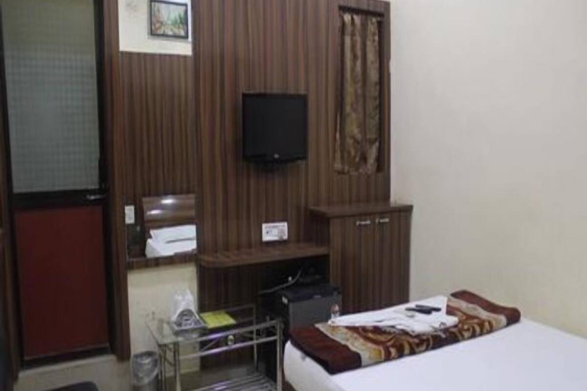A bedroom with a bed, a television, a wardrobe, and a small desk with a chair.