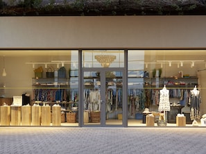A boutique with a glass storefront, displaying clothing and accessories.