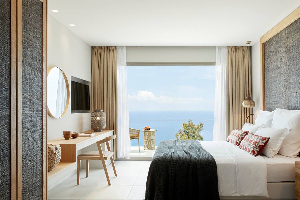Un dormitorio moderno con una cama grande, un escritorio y vistas al mar.
