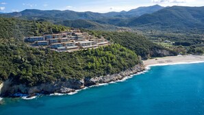 Rannikolla sijaitseva lomakeskus, jossa on useita rakennuksia, ranta ja sitä ympäröivät vuoret.