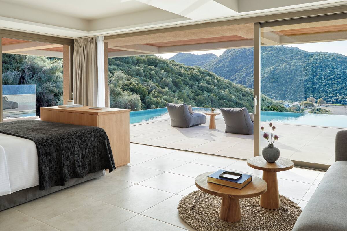 Un dormitorio moderno con una cama grande, un escritorio de madera y vistas a una montaña y un lago.