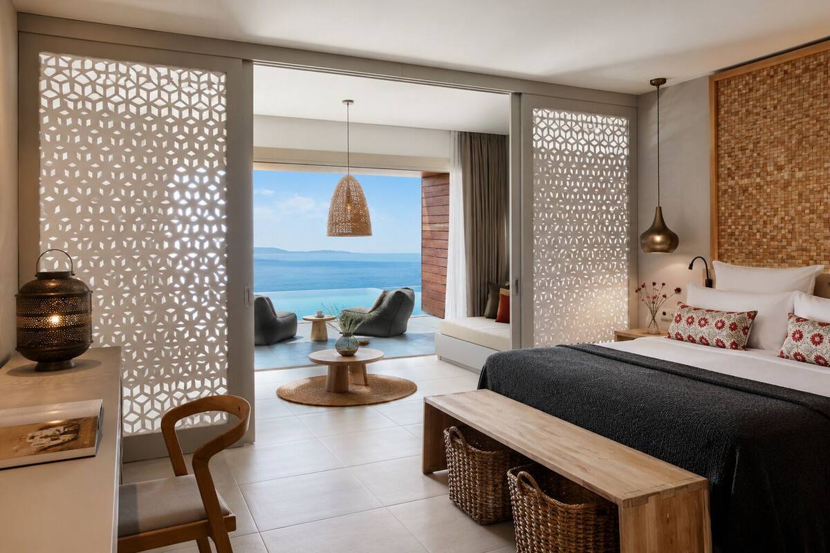 Un dormitorio moderno con una cama grande, un escritorio, una silla, una mesita redonda y vistas al mar.