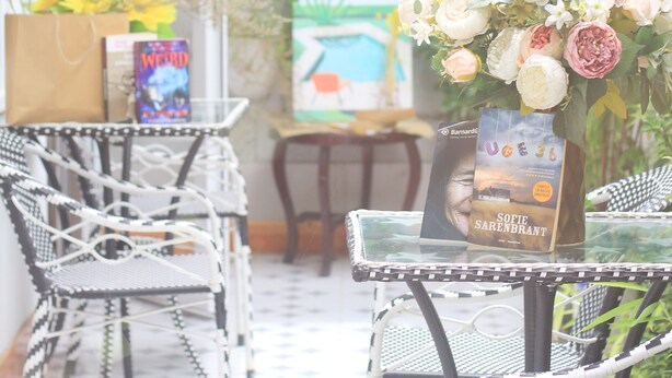 Un espace patio aménagé avec des fauteuils en osier, une table en verre et un vase de fleurs.