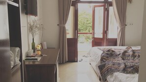 Une chambre avec un lit, un bureau, une télévision et une fenêtre avec des rideaux.