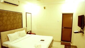 A hotel room with a bed, a TV mounted on the wall, an air conditioning unit, and a door with a mesh screen. - Pan Club Hotel (Vapi)