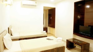 A hotel room with two beds, a TV, a small table, and an air conditioning unit. - Pan Club Hotel (Vapi)
