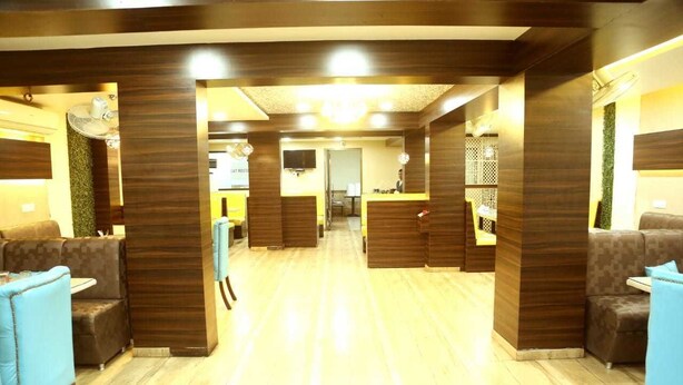 A hotel lobby with a central reception desk, seating areas, and a visible TV screen. - Pan Club Hotel (Vapi)
