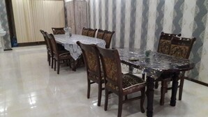 A dining area with a marble table and wooden chairs. - Nozisayyoh (Bukhara)