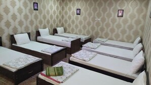A hotel room with four single beds, a small desk, and a patterned wallpaper. - Nozisayyoh (Bukhara)