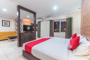Una habitación de hotel con cama, televisión, sofá y escritorio.