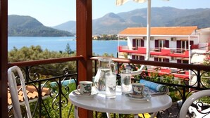 Un balcón con una mesa lista para dos personas, con vistas a un lago y edificios.