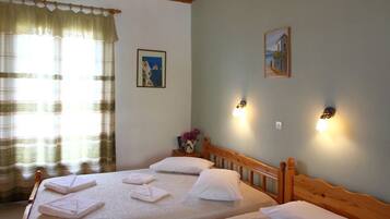 Una habitación con dos camas, cabecero de madera, ventana con cortinas e iluminación en la pared.