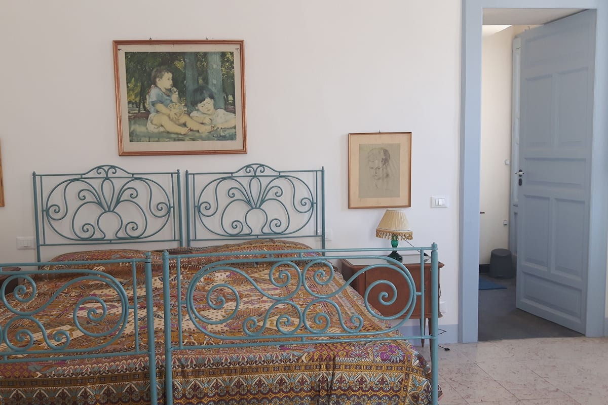 Quarto com uma cama, duas luminárias e duas molduras na parede.