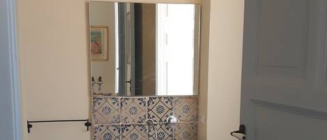 A bathroom with a white sink, a mirror above it, and a tiled backsplash.