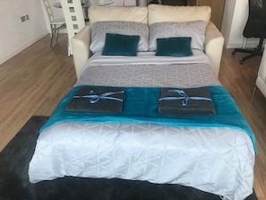 Un lit avec une couvre-lit à motifs, deux oreillers et deux serviettes pliées.