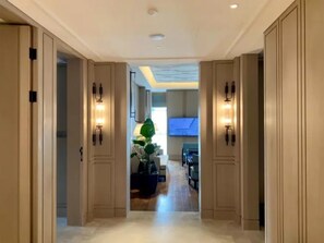 A hallway with double doors, recessed ceiling lighting, and a view into a dining area with a large plant and a television. - Yiu Teung Mansion (Chengdu)
