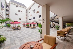 A hotel courtyard with outdoor seating, a staircase, and a view of the building's exterior. - Yiu Teung Mansion (Chengdu)