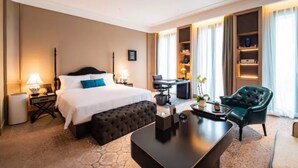 Hotellihuone, jossa on suuri sänky, työpöytä, tuoli ja sohvapöytä.