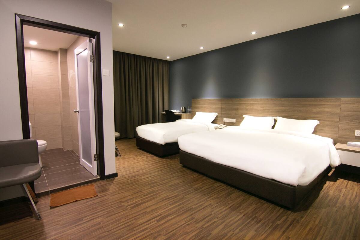Una habitación de hotel moderna con dos camas, un área de descanso y un baño.