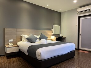 Een moderne hotelkamer met een groot bed, nachtkastjes, een bureau en een airconditioning.