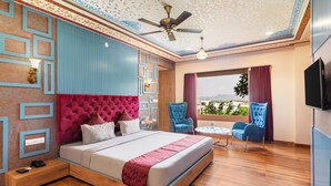 A bedroom with a bed, a ceiling fan, a TV, and a window with a view. - Vijaygarh Resort & Cottages with Private Pool (Udaipur)
