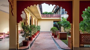 A corridor with tiled flooring, potted plants, and a balcony with a railing. - Vijaygarh Resort & Cottages with Private Pool (Udaipur)