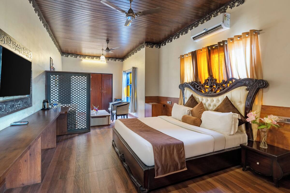 A hotel room with a large bed, a desk with a chair, a TV, and a decorative wall panel.