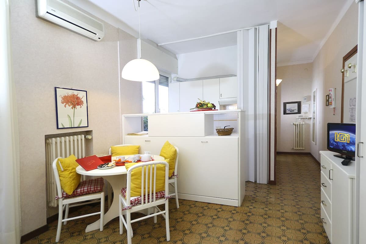 Una cocina compacta con comedor, un radiador, un televisor y piso estampado.