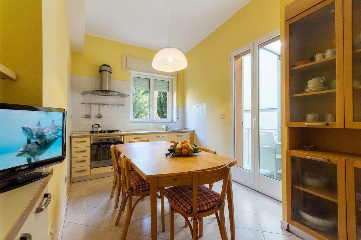 Una cocina con una mesa de comedor, sillas, un televisor y un armario.
