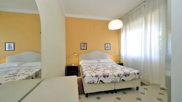 Una camera da letto con un letto, comodini, uno specchio e una finestra con tende.