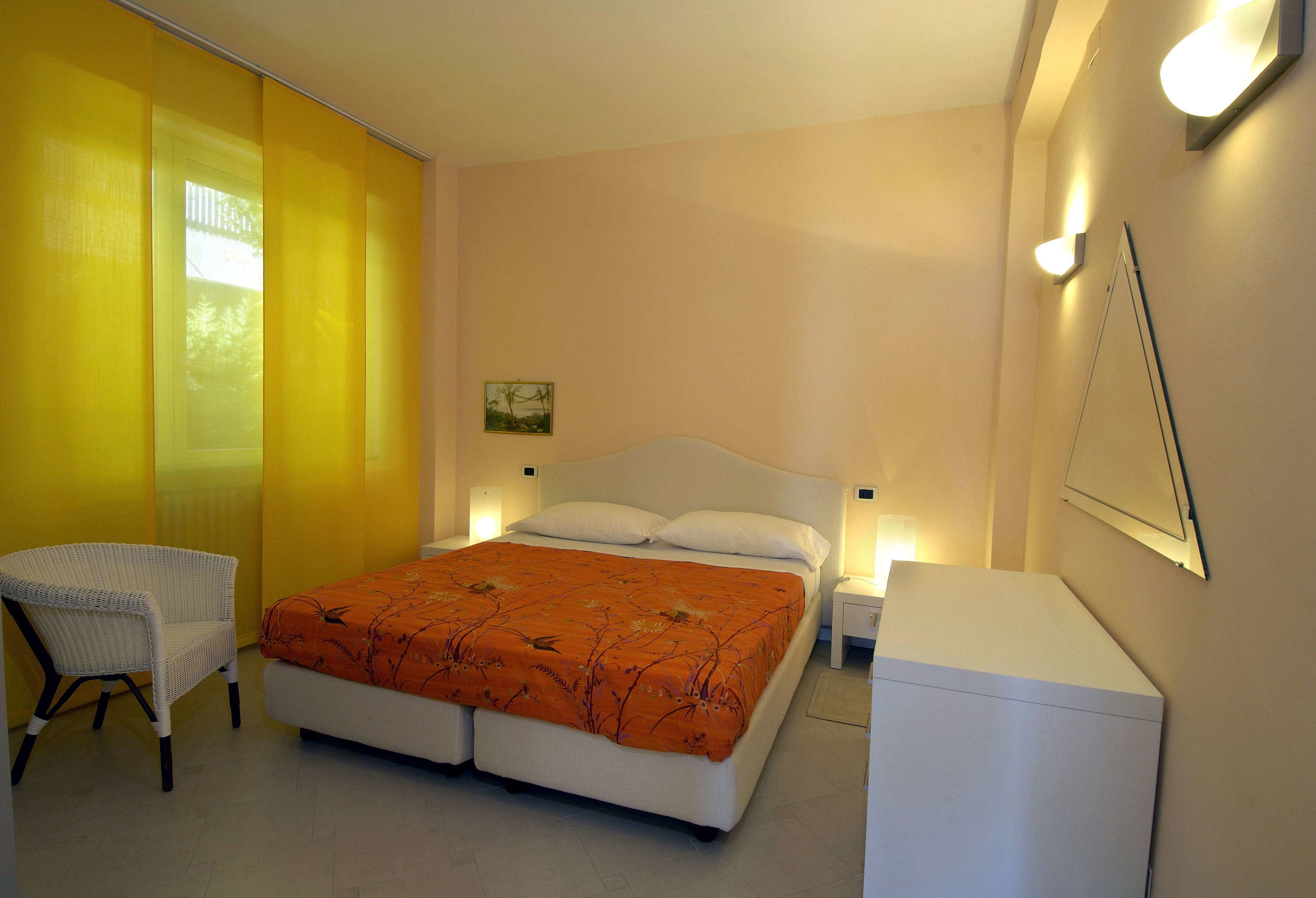 Ein Schlafzimmer mit Bett, Stuhl, Nachttisch und einem kleinen Schrank.
